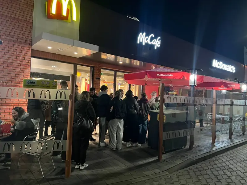 Tłum młodych ludzi czekających wieczorem przed restauracją McDonald's na sesję w Fotobudce AI - wynajem na promocje marek.